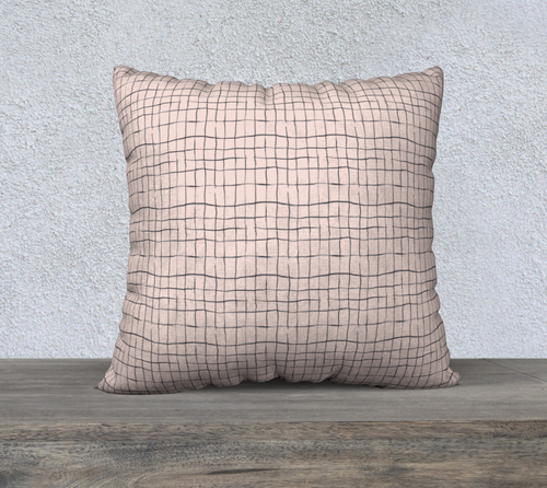 Decorative pillow with grid pattern on a wooden surface and light gray textured wall background