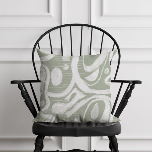 Green and white patterned pillow on a black chair against a white paneled wall.