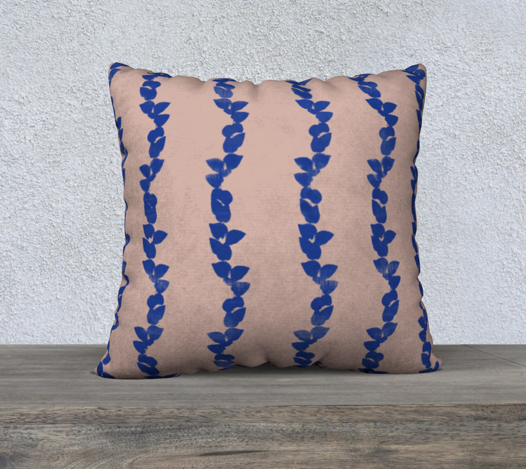 pink pillow with blue leaf pattern on a wooden surface and textured wall background